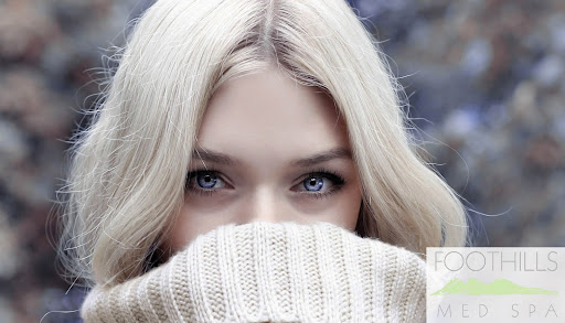 Blonde haired woman with an ivory sweater pulled above her nose
