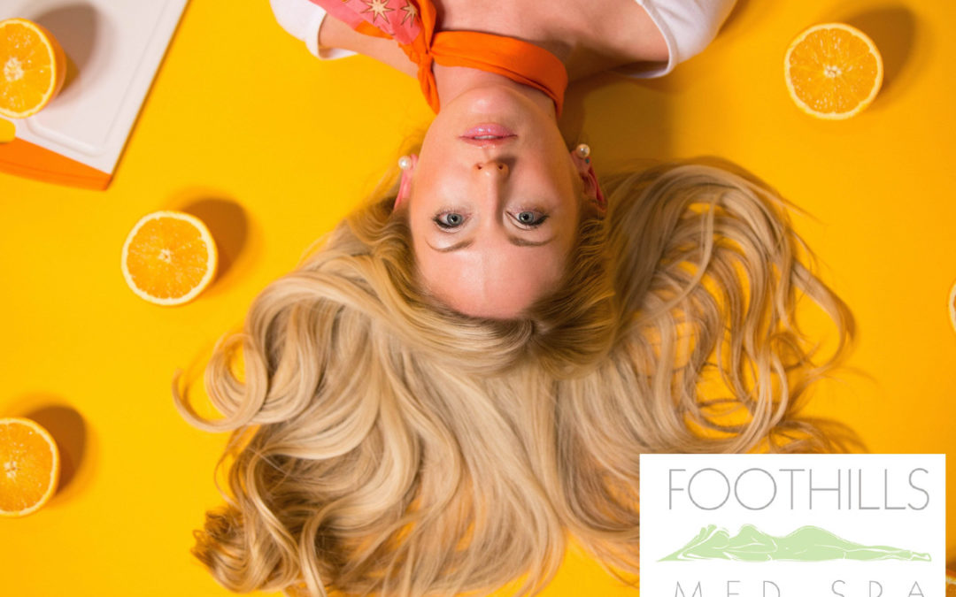 Blonde haired girl with hair laid out on an orange background with orange halves surrounding her.